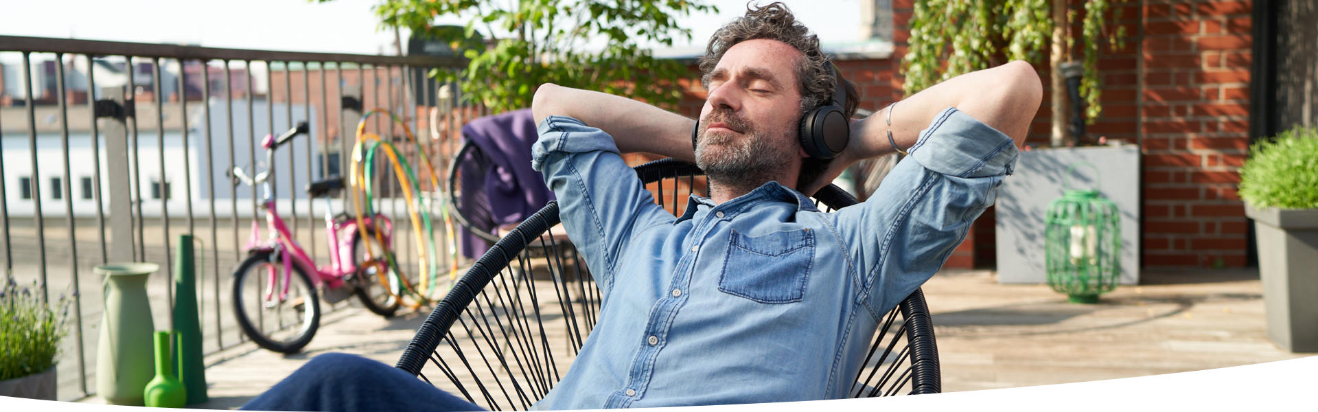 Mann hört entspannt Musik auf der Terrasse